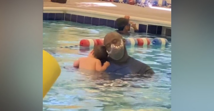 man holding a baby in a pool as they the baby rests his head on his shoulder