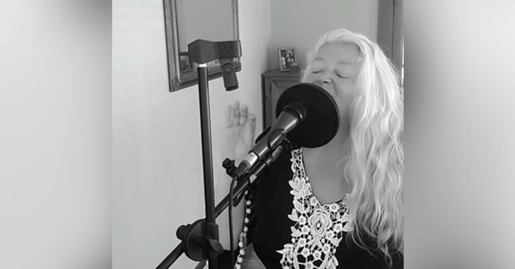 black and white photo of woman singing into mic
