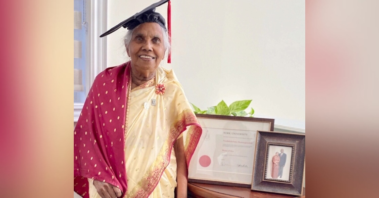 87 year old varatha shanmuganathan smiling while wearing her graduation cap and posing with her master's degree from york university