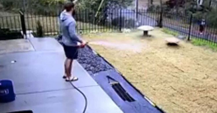 man watering lawn while waving at neighbor on street