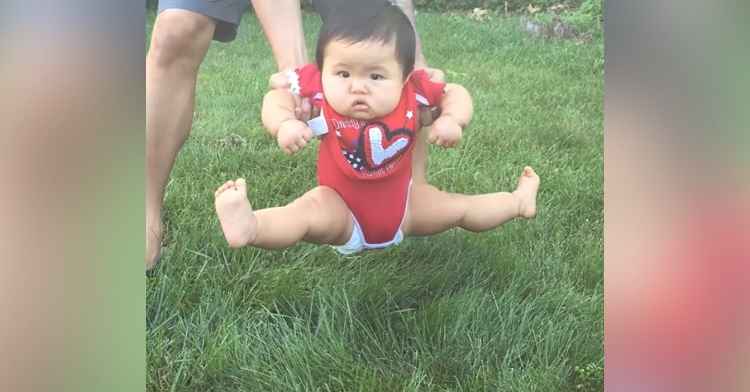 baby being held above grass as they do the splits to avoid touching the grass