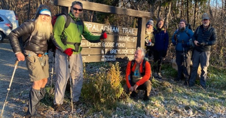 nimblewill nomad posing with an appalachian trail sign with other hikers