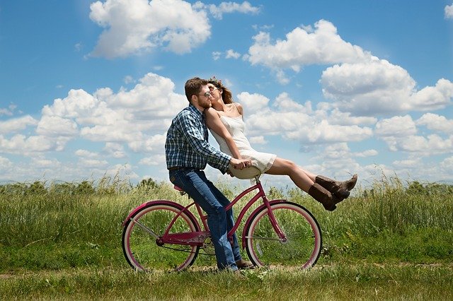 man and woman kissing while riding a bicycle