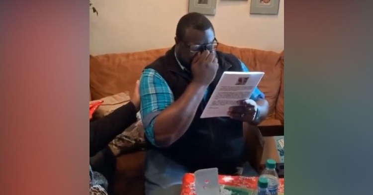 daryl elliot jr rubbing his eyes and crying as he looks at his published book "barney the boring barumbus"
