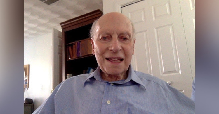 89 year old physicist manfred steiner sitting in a room and smiling