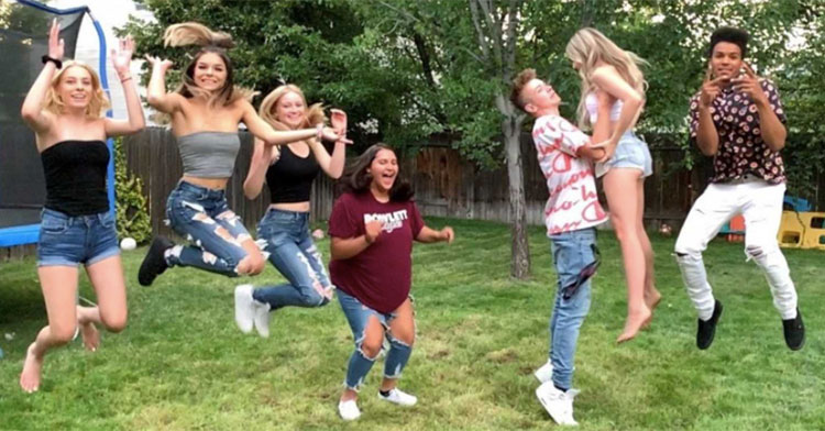 a group of teens jumping in backyard