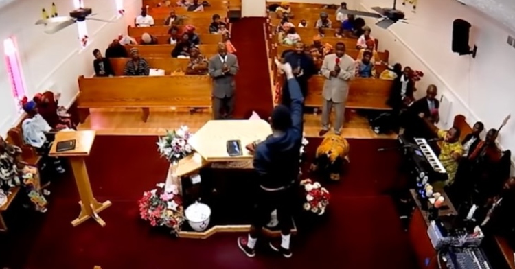 dezire baganda standing at the pew of the nashville light mission pentecostal church while waving around a gun in the air