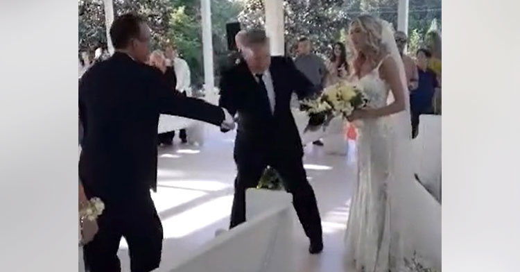 dad who is walking his daughter down the aisle stopping to grab the arm of her stepdad so he can join them
