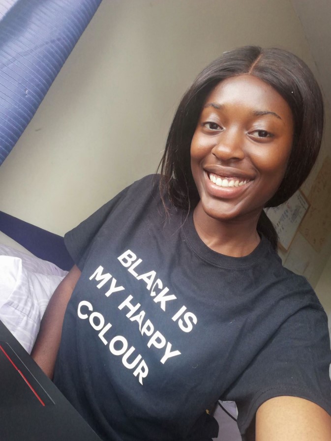 woman smiling and wearing a black shirt that says "black is my happy colour"