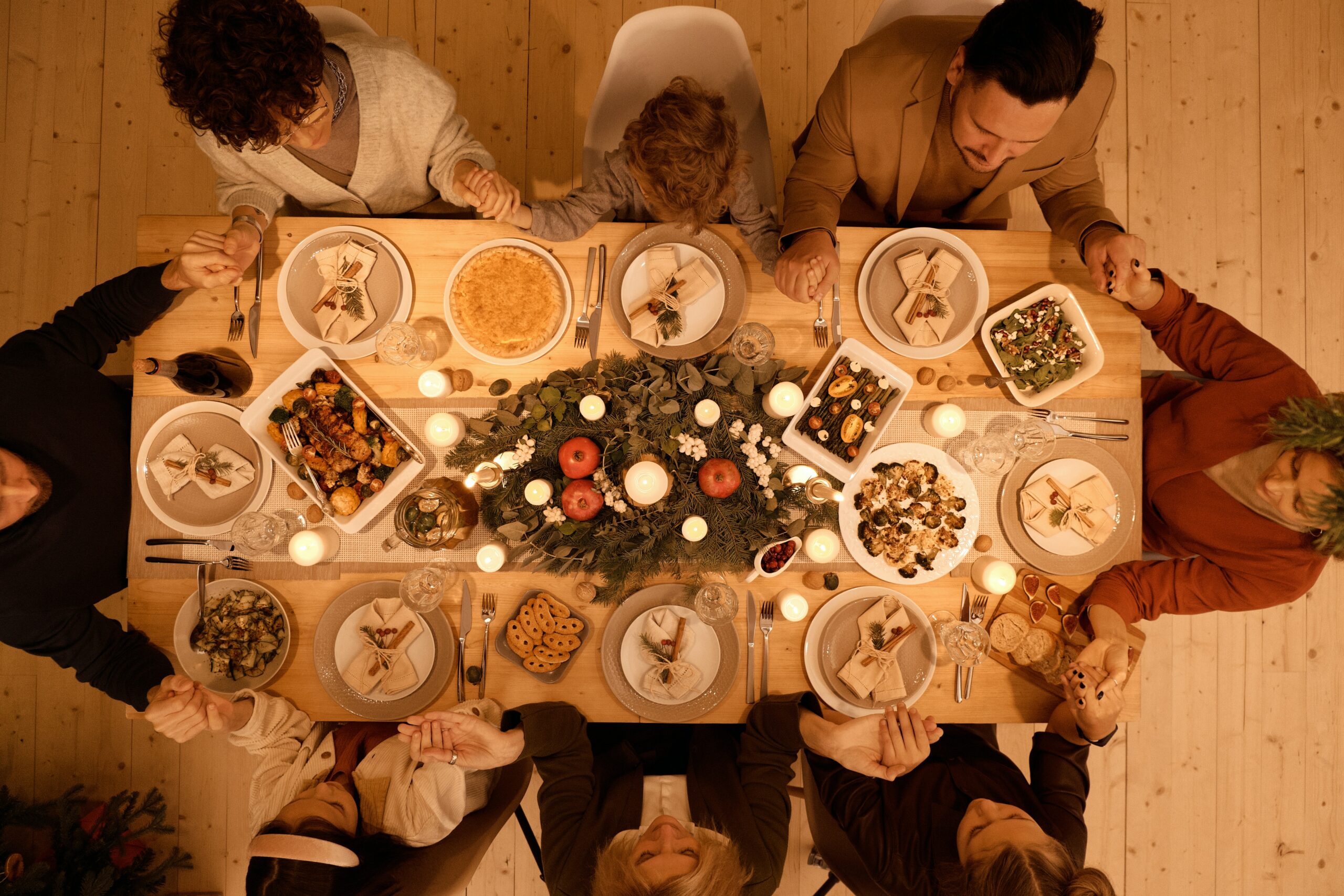 An overhead picture of a family saying grace before a holiday meal