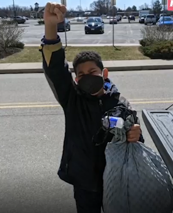 Josiah Colton wearing mask and holding bag of recycling
