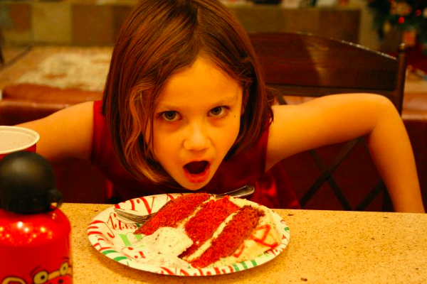 Kaylee as a kid posing next to a piece of the cake.