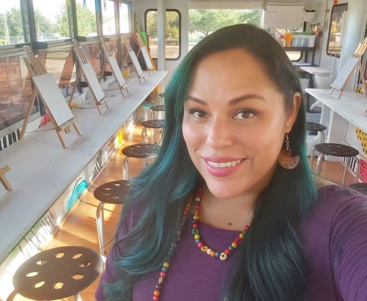 woman named veronica cabrera-moreno smiling while sitting on a renovated school bus turned mobile art studio from htx art