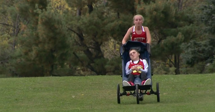 sister pushing brother in wheelchair across field