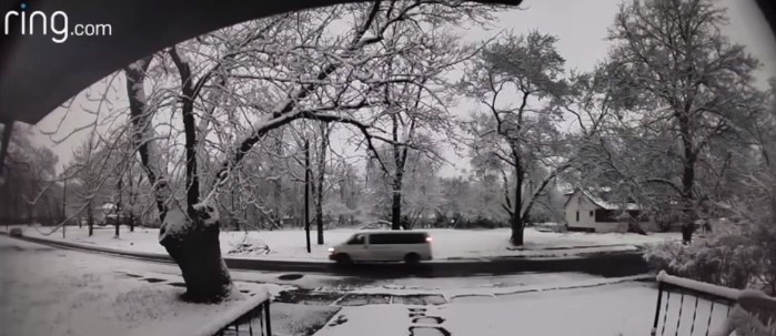 snow covered yards with a white van driving down the road from the view of a ring camera