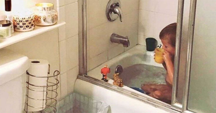 little boy sitting in tub drinking from cup