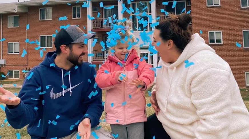 man named adrian fuentes smiling and throwing confetti with his wife, marissa fuentes, and their toddler, ellianna
