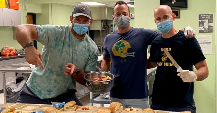 former nfl player jared veldheer posing in a face mask with two other men in the cafeteria of st. paul the apostle school