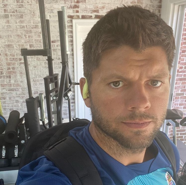 former nfl player jared vedheer taking a selfie with workout equipment in the background