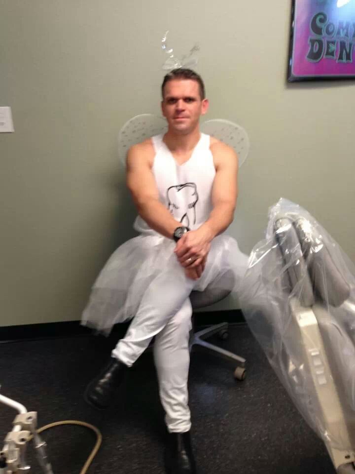 dentist sitting on a chair with his legs crossed while wearing a tooth fairy uniform with wings 
