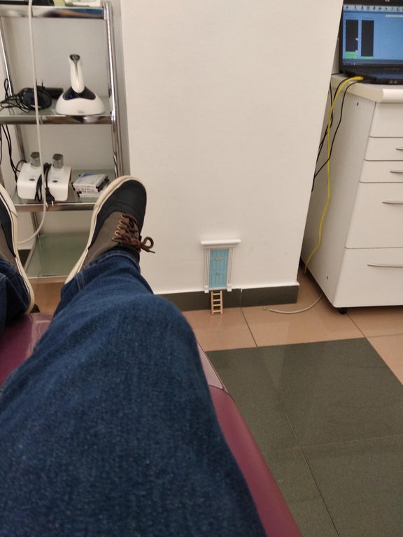 view of a small mouse-size door with a ladder from the perspective of someone laying on a dentist's chair 