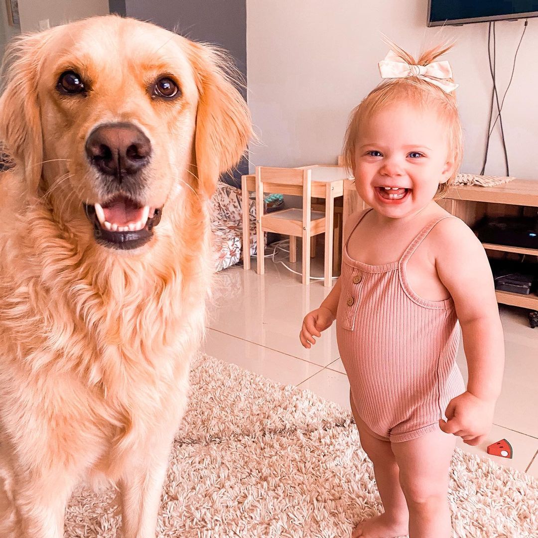 large, happy dog named marshall posing with a baby girl named macy who is standing and smiling