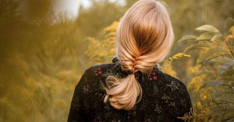 woman with braided hair standing near leafy trees