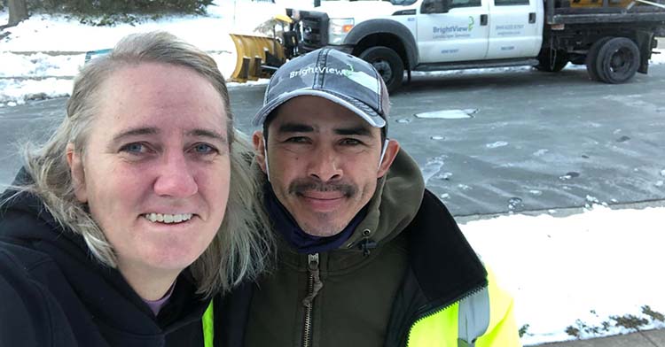 woman standing next to landscaping employee on snowy street