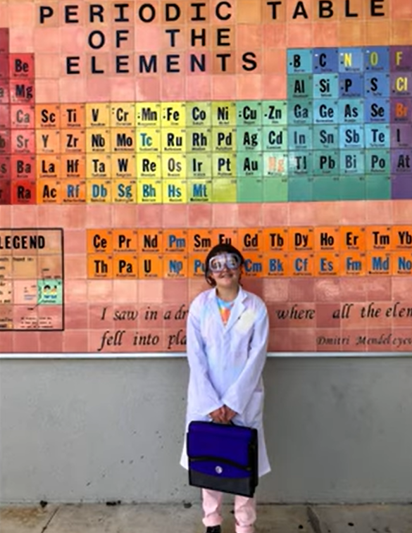 Sawsan Ahmed stands in front of a large periodic table of elements