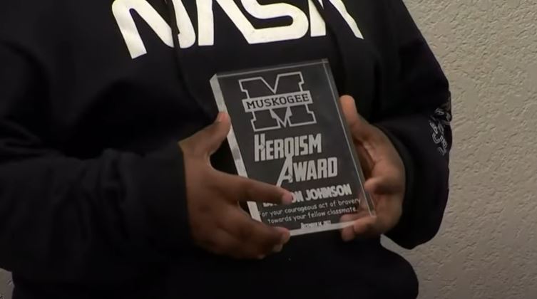 Davyon hold an award reading "heroism award"