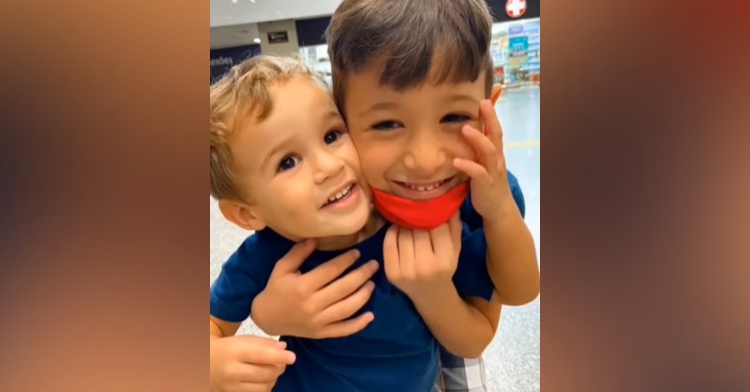 closeup of two little boys hugging as they smile and pose for a photo