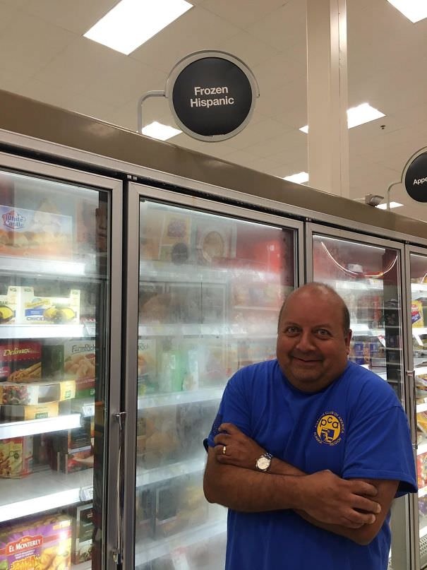 a hispanic man standing in a grocery aisle under the sign 