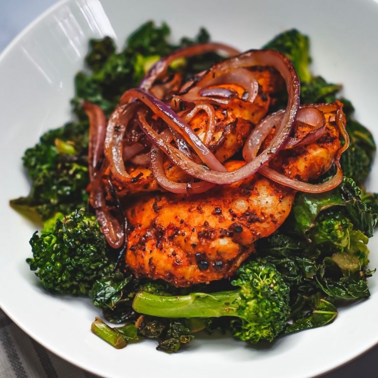 a photogenic plate of boneless chicken thighs, sauteed broccoli, and sauteed kale which was made by a woman named camille jones