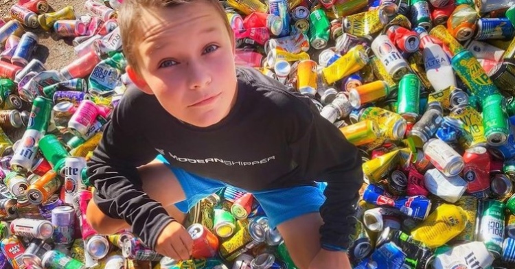 12 year old boy named cash daniels posing on top of a pile of cans he's recycling