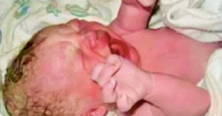 newborn baby crying on sheet with hands raised