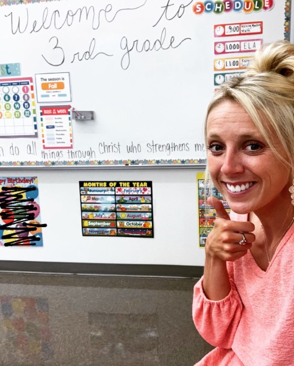 woman named kathleen fitzpatrick giving a thumbs up and smiling in front of her classroom white board