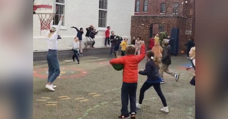 woman named kathleen fitzpatrick along with her third grade students raising their arms in celebration after she made a full-court basketball shot