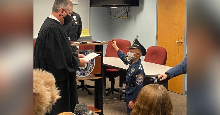 an 8 year old boy named landen being sworn in as a police officer by the district justice