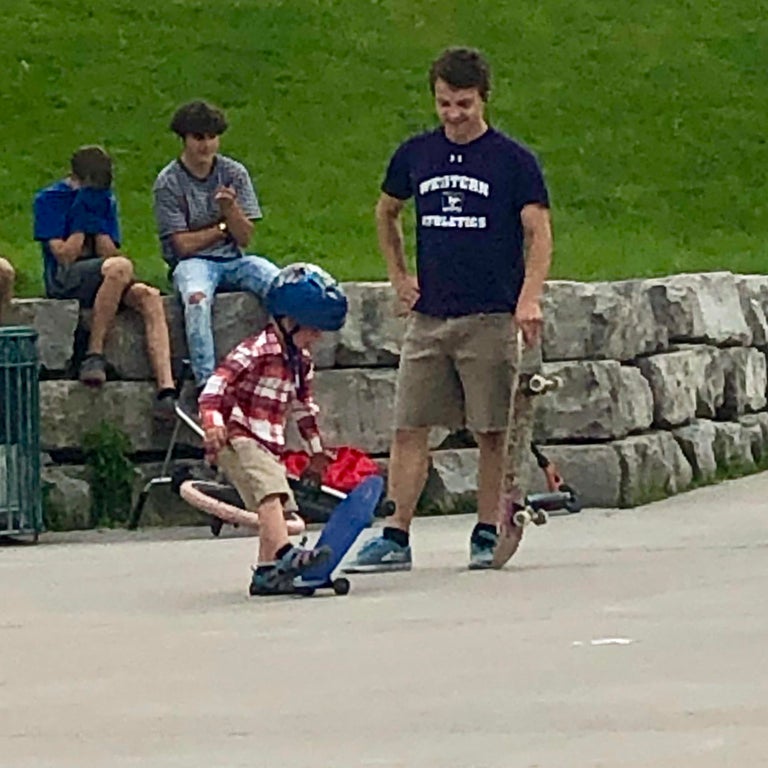 teens helping kid skateboard