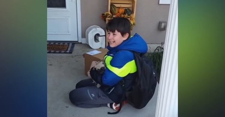 a little boy named peyton looking back and smiling as he holds the puppy pug his parents just gave him