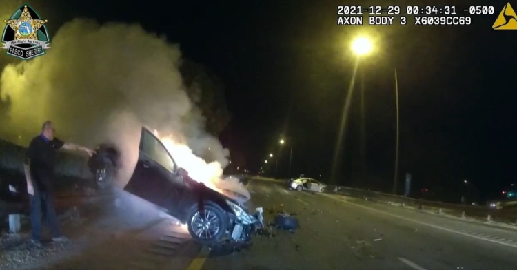 police body cam footage from pasco sheriff's office of a car that had crashed and is now on fire on the side of the road