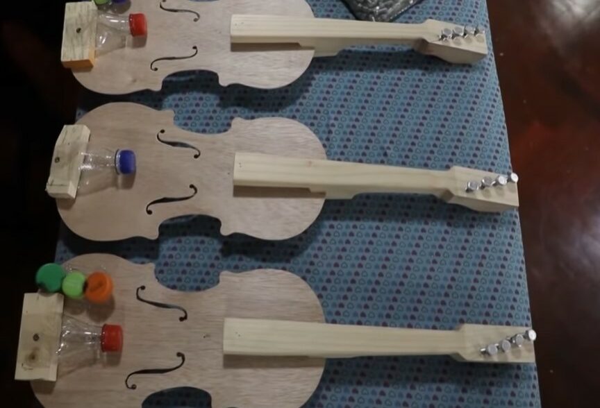 three violins made out of recycled materials that were made by  jesÃºs peralta and named bottlephone violins