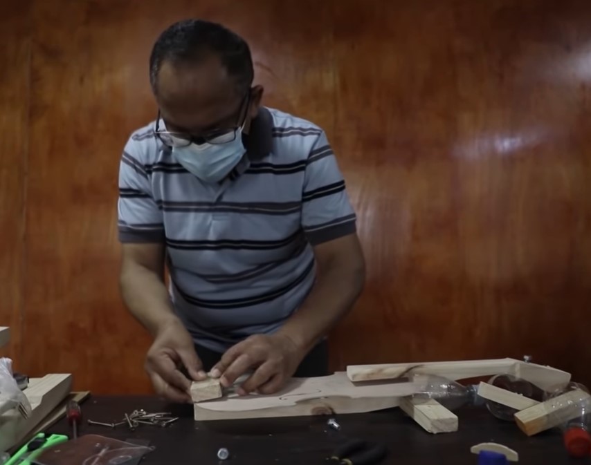 a 68 year old man named jesÃºs peralta wearing faces masks as he works to build a violin out of recycled materials that he called bottlephone violins
