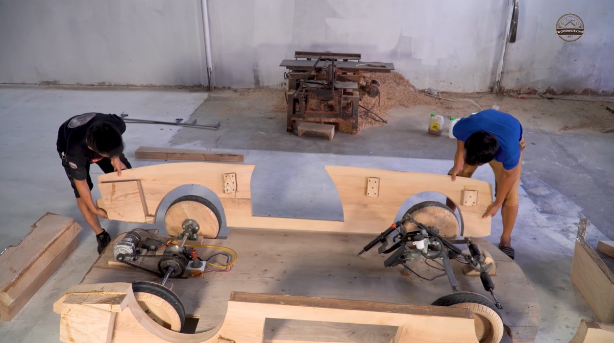 a man named trÆ°Æ¡ng vÄƒn dáº¡o and a second man working together to put into place a component of the mini wooden rolls-royce boat tail replica they're making