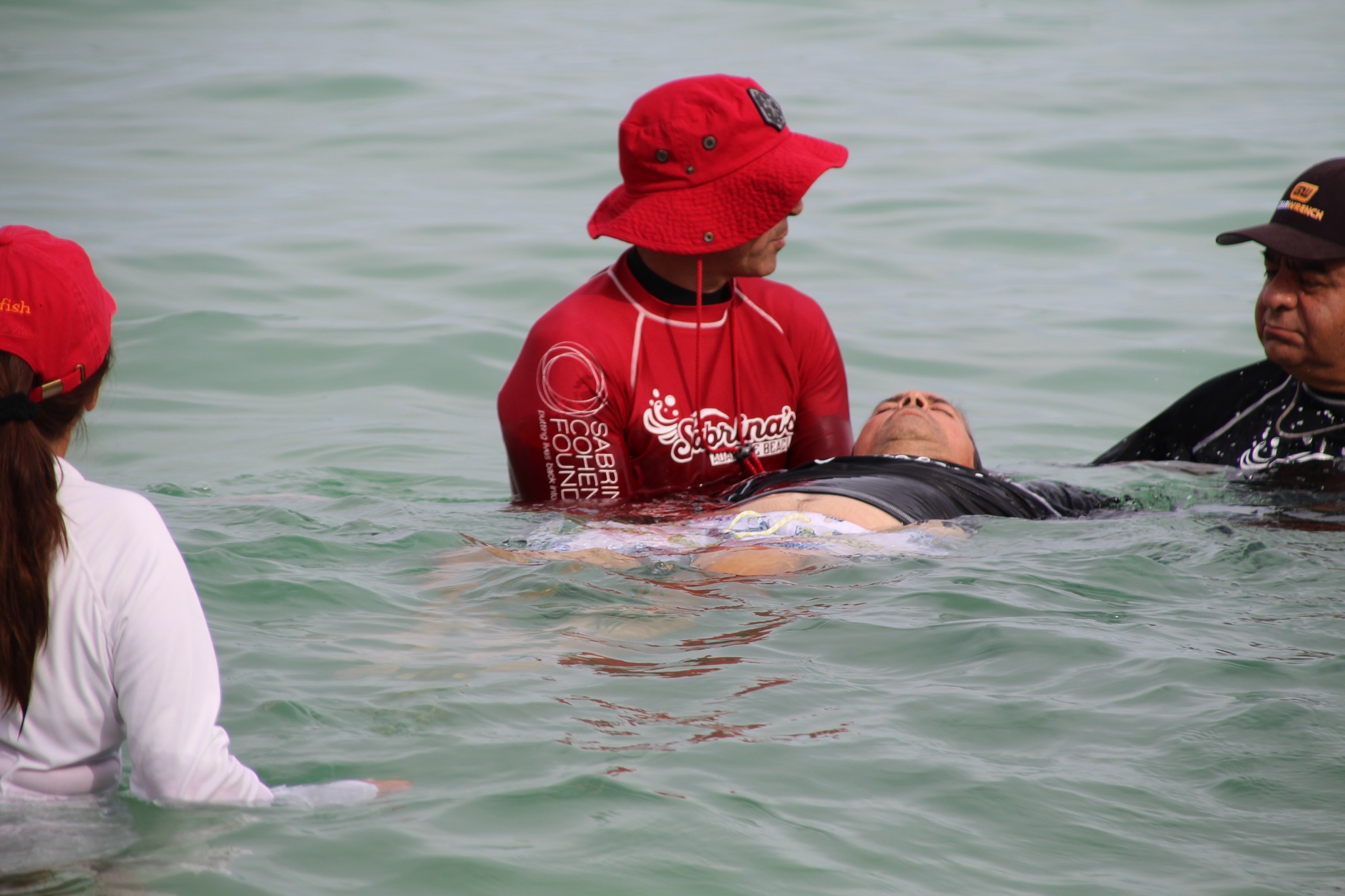 a volunteer for the sabrina cohen foundation helping keep someone afloat in the ocean at the city of miami beach