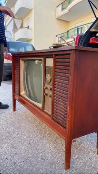 an old fashioned box tv outside on a driveway 