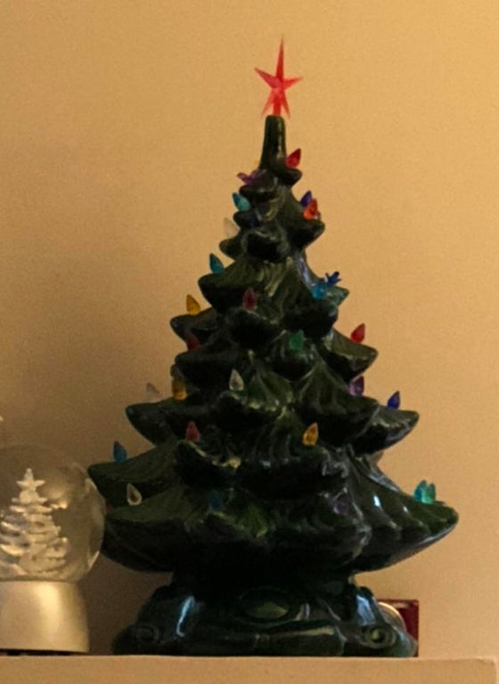 closeup of a small ceramic christmas tree that's sat next to an even smaller silver snow globe with a snow covered tree inside 