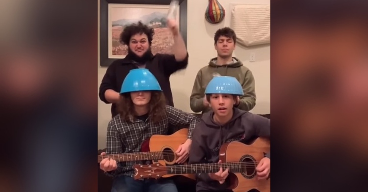 the members of the band adam and the metal hawks playing music together, two of which are sitting, playing guitars, and wearing bowls on their head while the other two stand behind them and hold empty water bottles