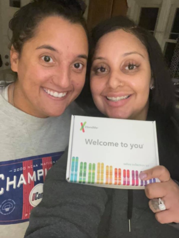 sisters named julia tinetti and cassandra madison smiling and posing with a 23andme box