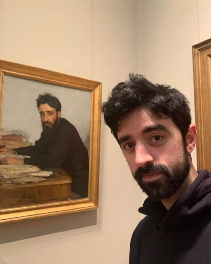man with a beard posing with a work of art featuring a man who looks just like him